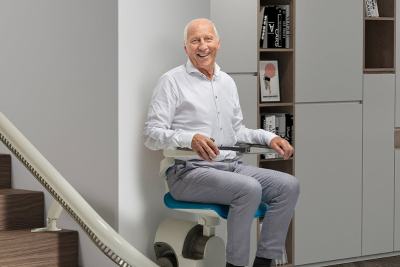 Man seated on a blue and white stairlift chair