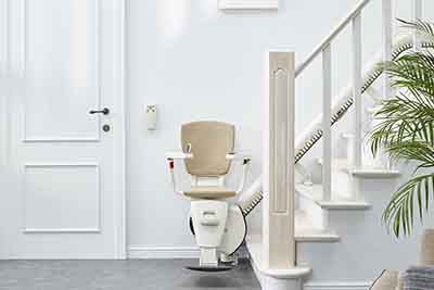 Empty stairlift pictured at the bottom of the stairs next to a door