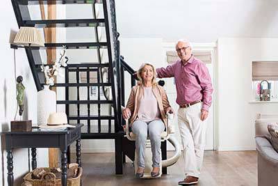 Man with arm over woman on stairlift on the left side of the stairs