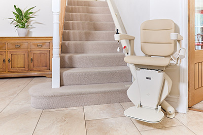 Light brown stair lift at bottom of stairs